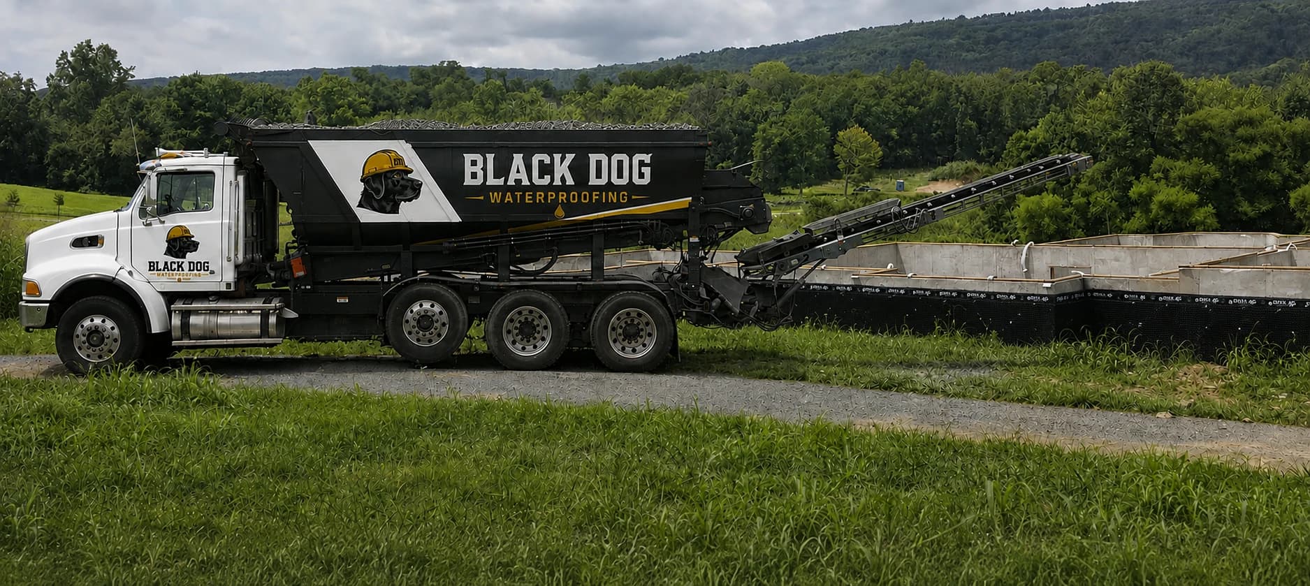 Black-and-white stone slinger positioned beside a foundation with its conveyor extended